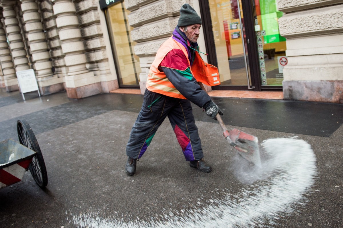 A Fővárosi Közterület-fenntartó Zrt. (FKF Zrt.) munkatársa csúszásgátló anyagot szór a járdára Budapest belvárosában. MTI Fotó: Balogh Zoltán