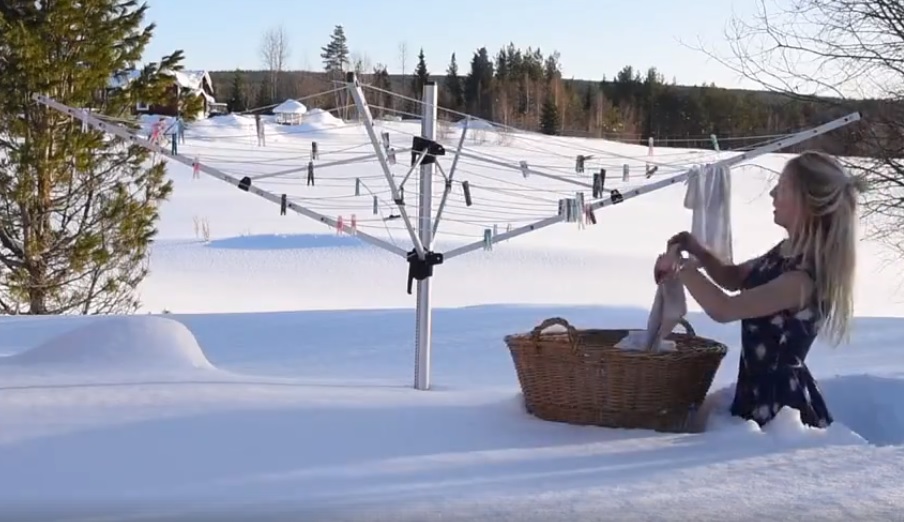 Derékig érő hóban, nyári ruhában teregetett egy nő – videó