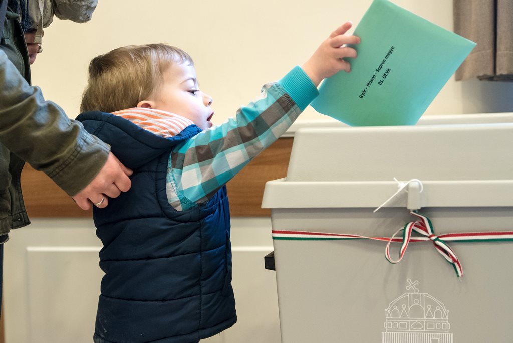 Egy választópolgár gyermeke segítségével leadja szavazatát a csíkszeredai magyar főkonzulátuson az országgyűlési képviselő-választáson 2018. április 8-án. MTI Fotó: Veres Nándor